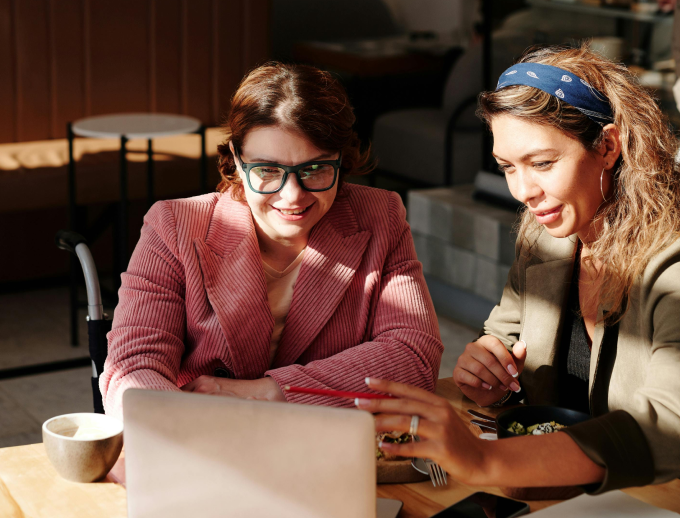 a group of women sitting at a table looking at a laptop